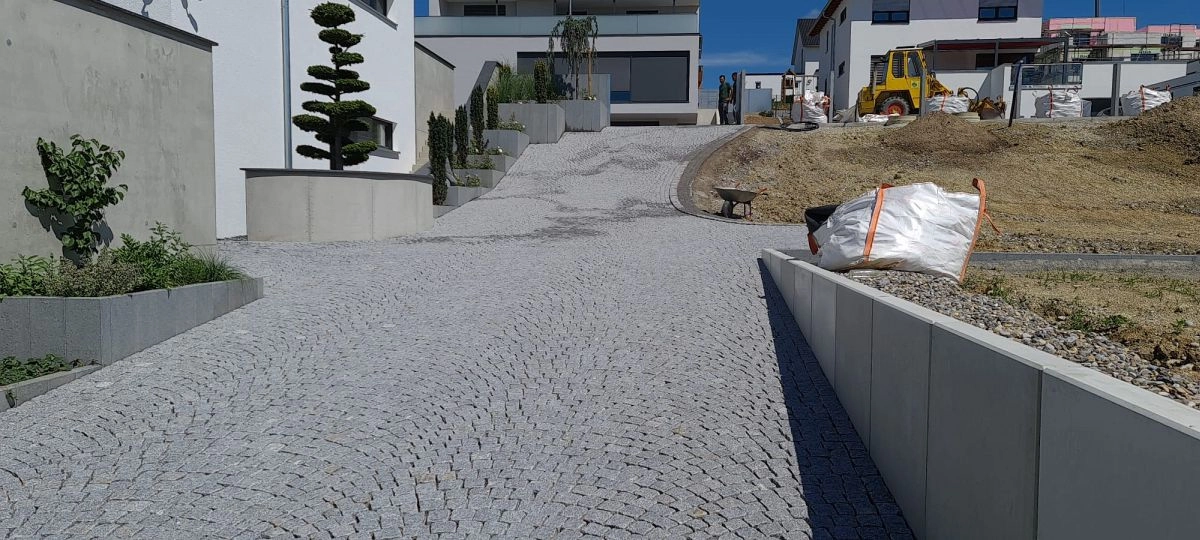 Gepflasterter Gehweg-Aufgang aus Naturstein zwischen modernen Wohnhäusern
